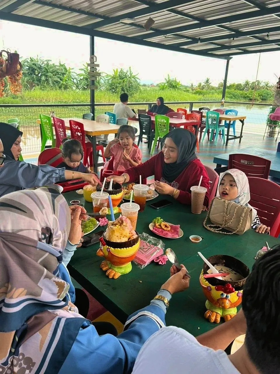 Keluarga pelanggan bersantai makan tepi sungai